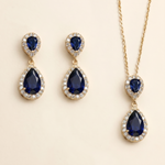 A set of elegant jewelry pieces, including earrings and a necklace, featuring large blue gemstones and sparkling diamonds.