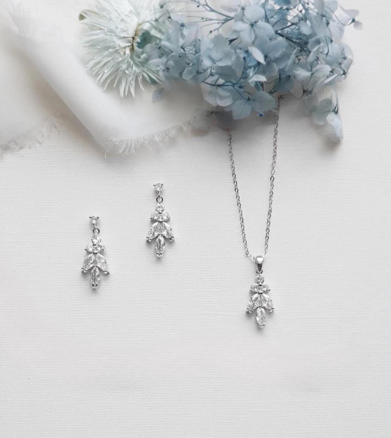 a necklace and earrings with a floral design, placed on a white background.