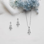 a necklace and earrings with a floral design, placed on a white background.