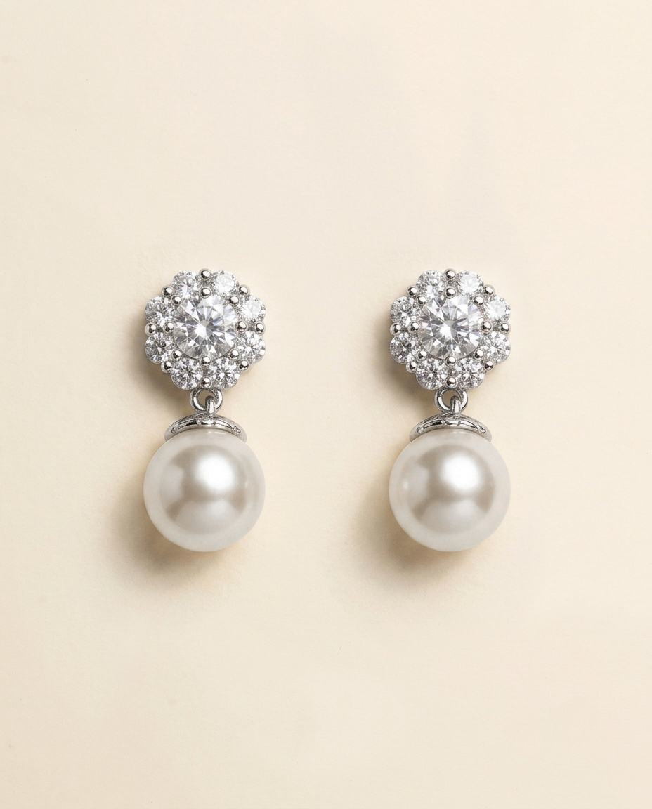 A pair of elegant earrings with a large, round pearl at the bottom and a cluster of smaller pearls on top, set against a light beige background.