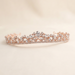 A delicate, ornate gold-colored tiara adorned with numerous small diamonds.
