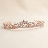 A delicate, ornate gold-colored tiara adorned with numerous small diamonds.