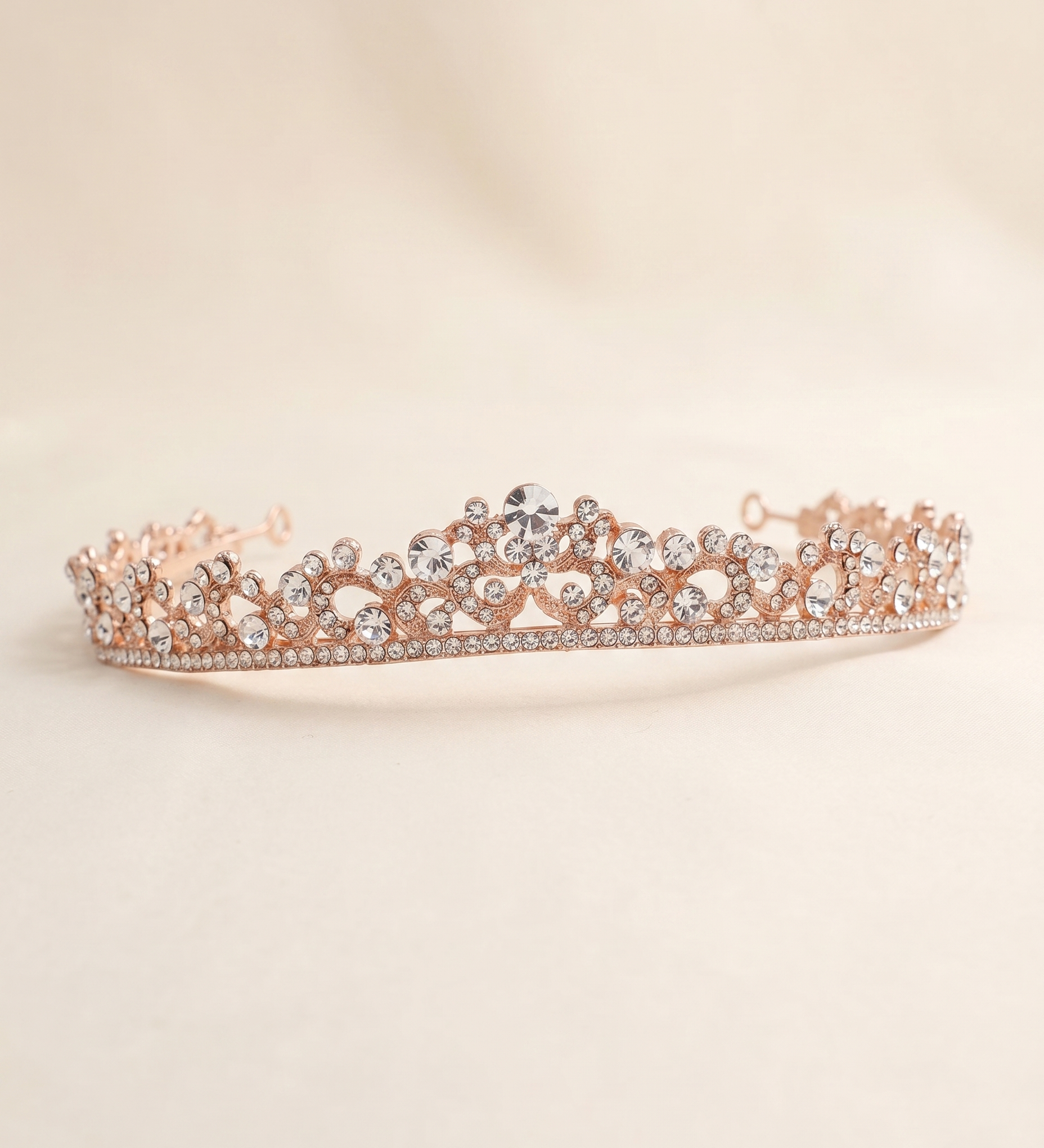A delicate, ornate gold-colored tiara adorned with numerous small diamonds.