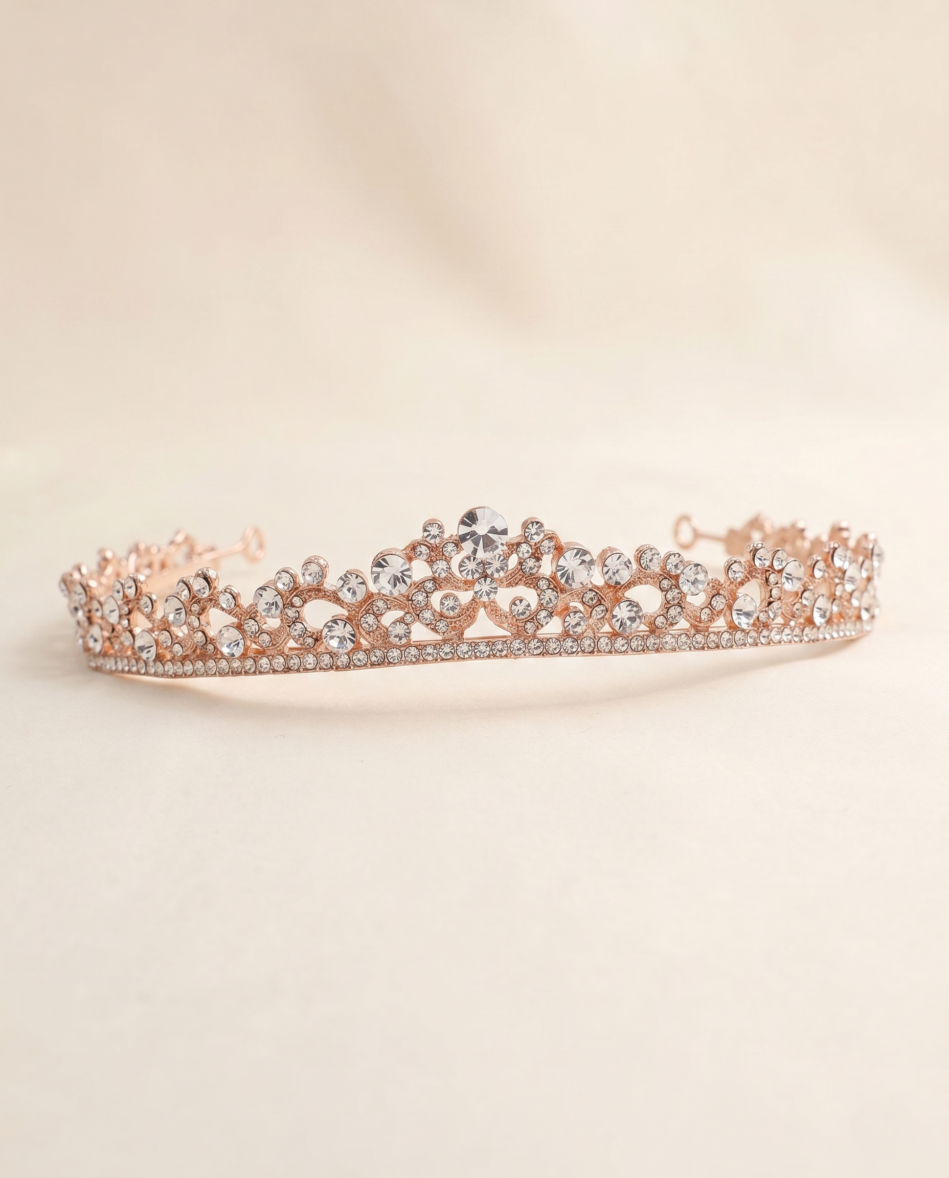 A delicate, ornate gold-colored tiara adorned with numerous small diamonds.
