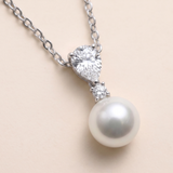 A necklace with a pearl pendant and a large diamond set in the center.