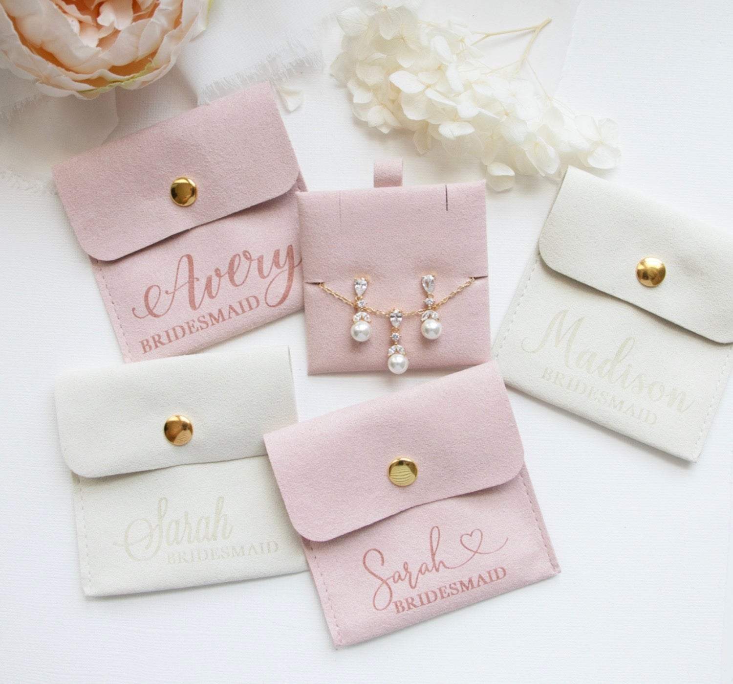 a collection of bridesmaid jewelry and accessories, including earrings and purses, arranged on a white background.