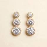 A pair of elegant gold earrings with three tiers of round, sparkling diamonds.