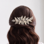 the back view of a woman's head with a decorative hair accessory, featuring a combination of pearls and leaves.