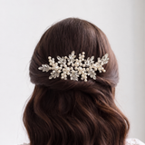 the back view of a woman's head with a decorative hair accessory, featuring a combination of pearls and leaves.