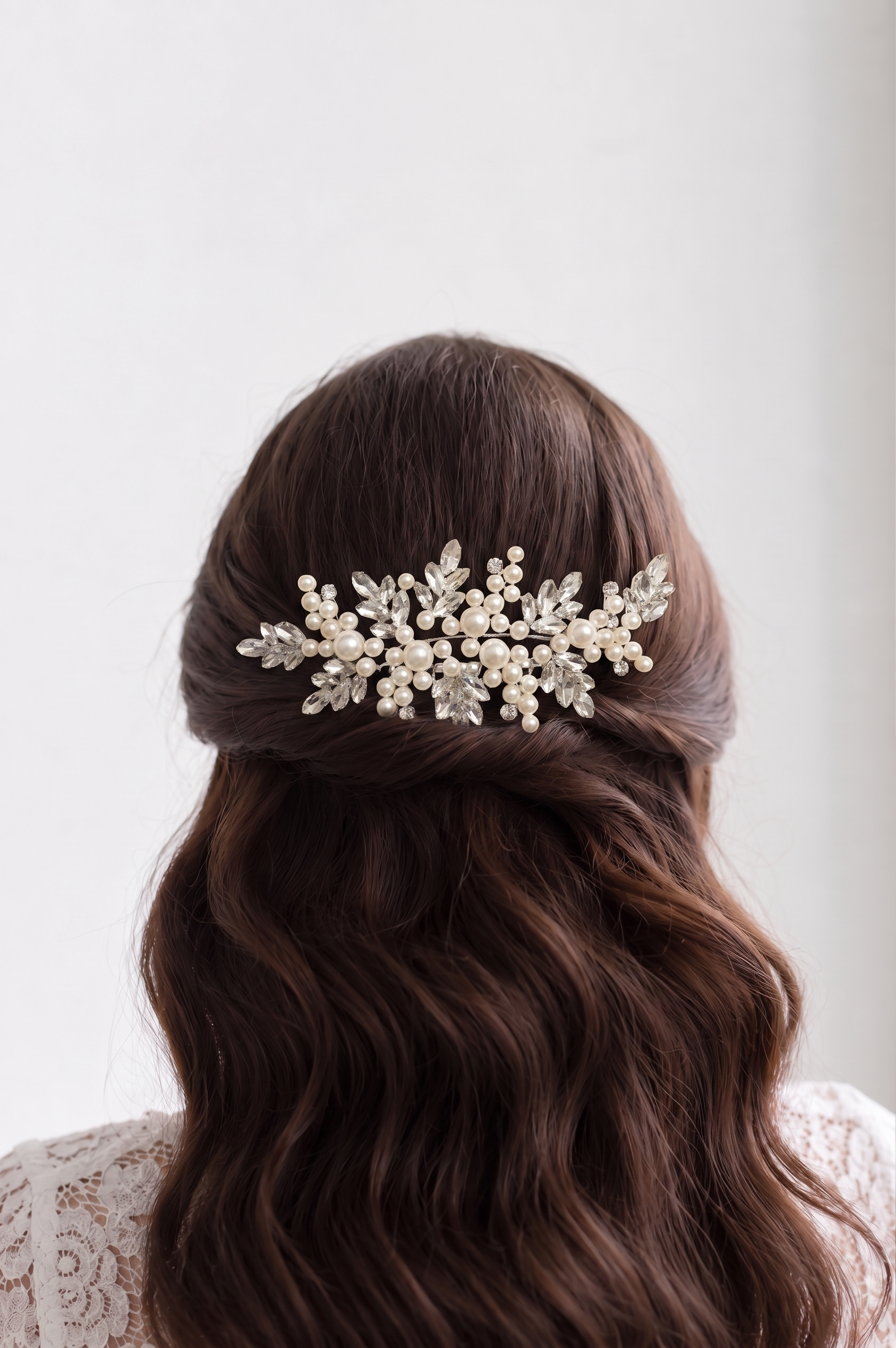the back view of a woman's head with a decorative hair accessory, featuring a combination of pearls and leaves.