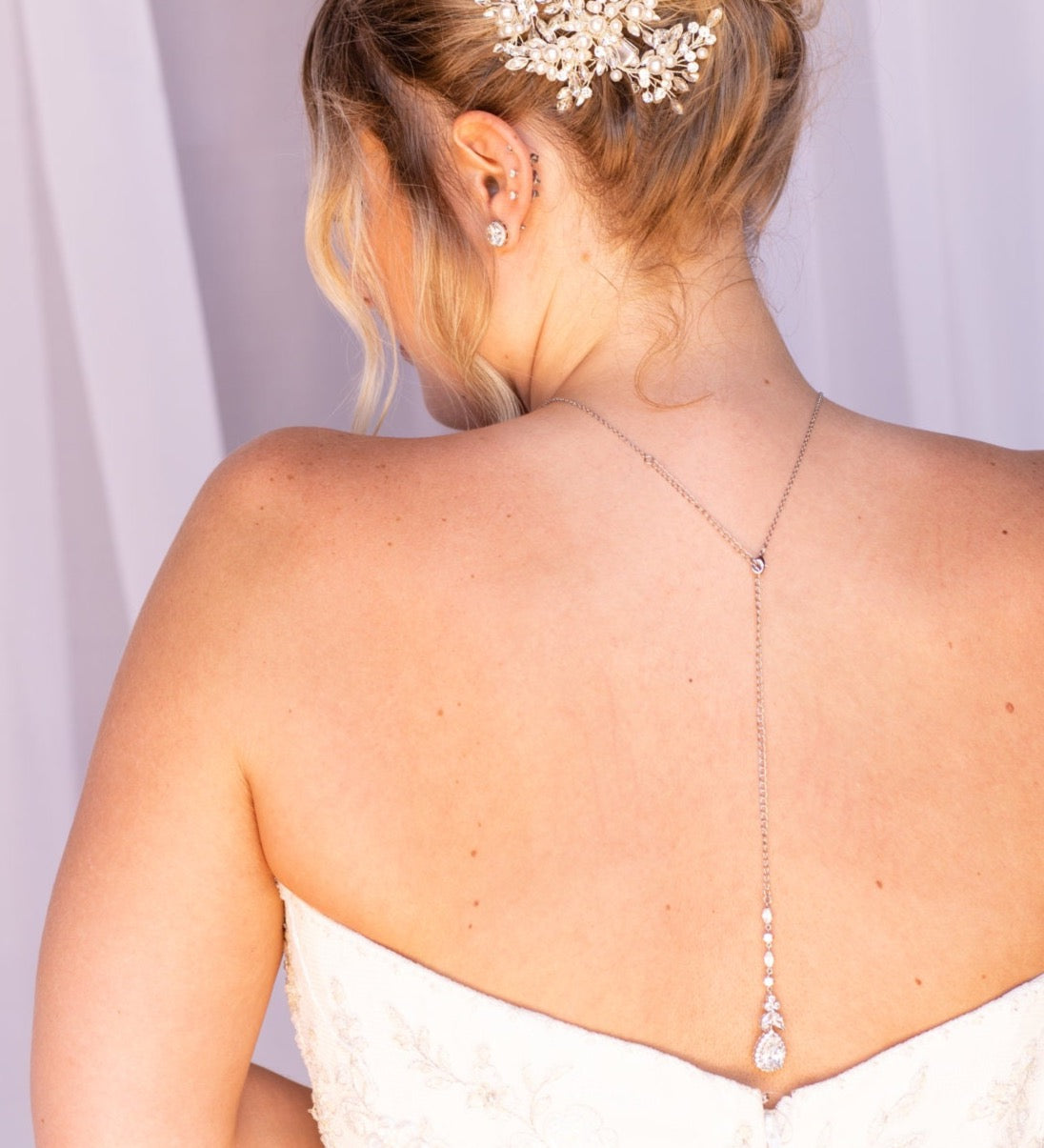 the back of a woman wearing a white strapless wedding dress with a delicate flower hair accessory.