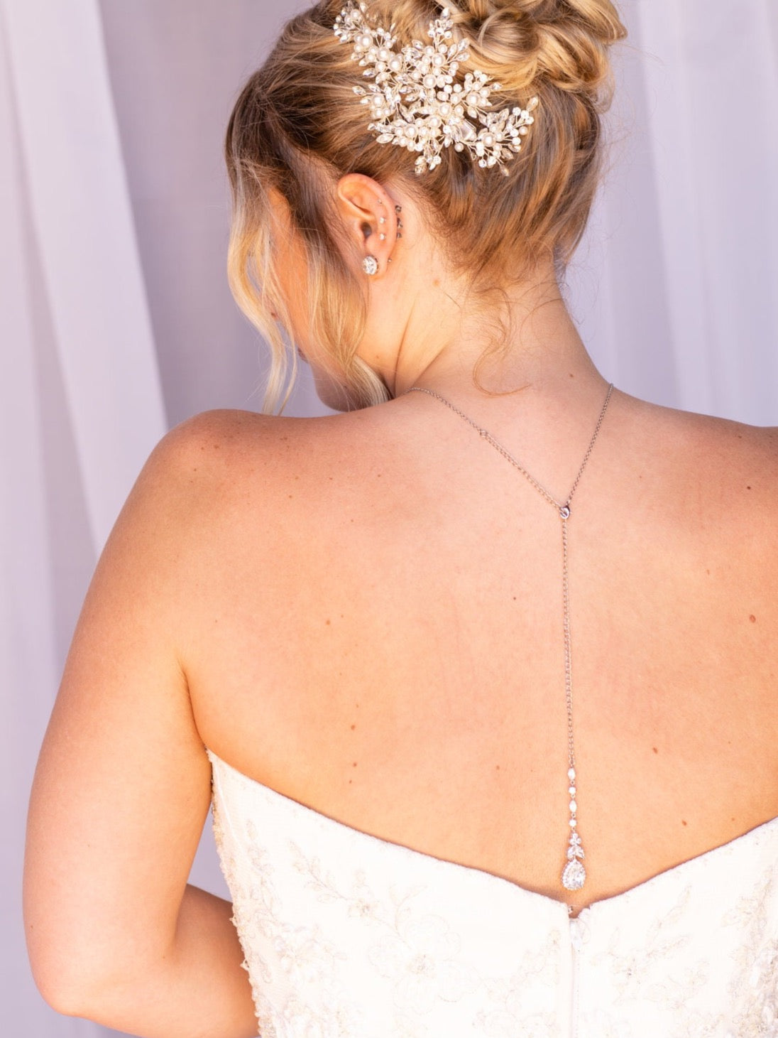 the back of a woman wearing a white strapless wedding dress with a delicate flower hair accessory.