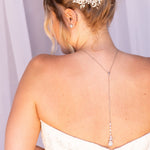 the back of a woman wearing a white strapless wedding dress with a delicate flower hair accessory.