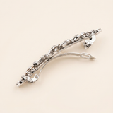 A silver hair clip with a decorative design and multiple small diamonds or gemstones.