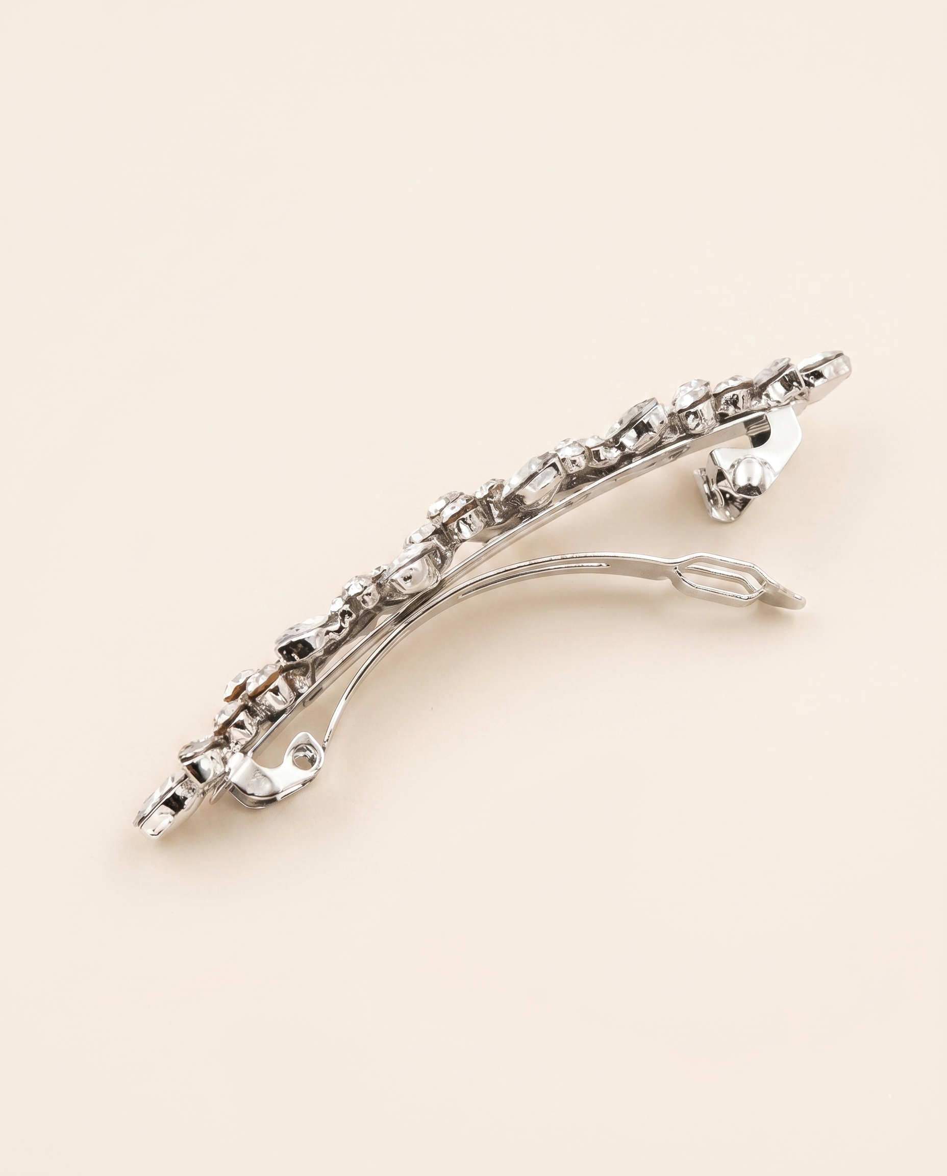 A silver hair clip with a decorative design and multiple small diamonds or gemstones.