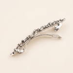 A silver hair clip with a decorative design and multiple small diamonds or gemstones.