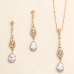 A set of three gold-colored jewelry pieces, including earrings and a necklace, with clear gemstones.