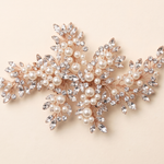 a decorative piece of jewelry with a combination of pearls, crystals, and leaves.