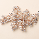 a decorative piece of jewelry with a combination of pearls, crystals, and leaves.