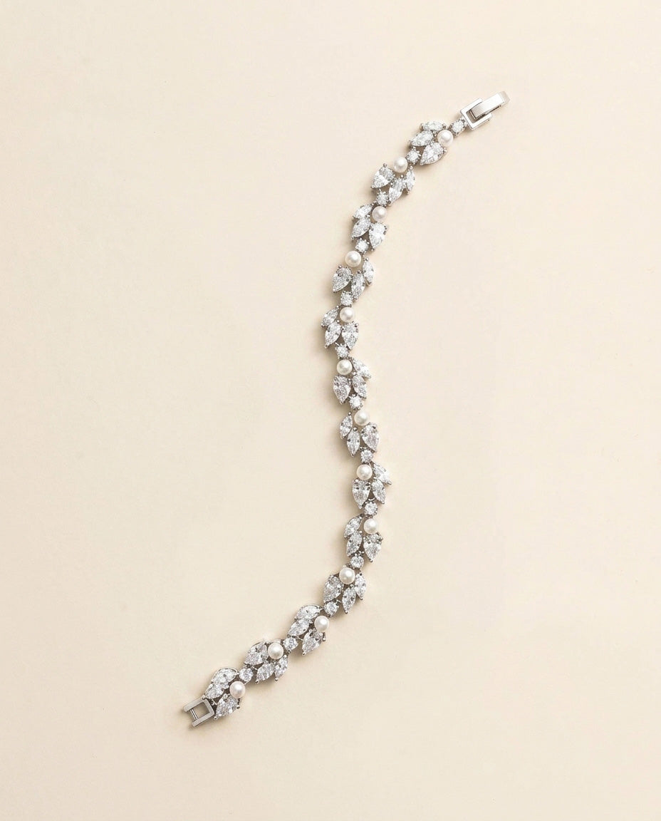 A silver bracelet with numerous small diamonds and pearls arranged in a decorative pattern.