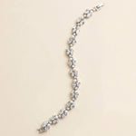 A silver bracelet with numerous small diamonds and pearls arranged in a decorative pattern.