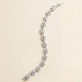 A silver bracelet with numerous small diamonds and pearls arranged in a decorative pattern.
