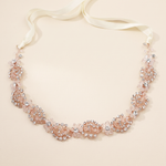A delicate necklace with a white ribbon and a floral design made of small, clear, and pink-colored stones.