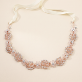 A delicate necklace with a white ribbon and a floral design made of small, clear, and pink-colored stones.