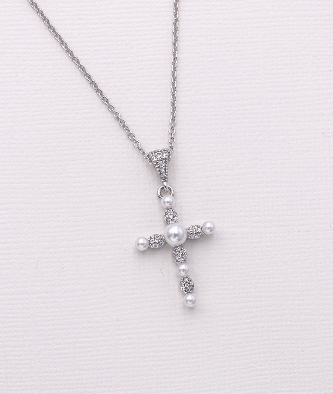 A silver cross pendant necklace with pearls and diamonds.