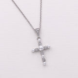 A silver cross pendant necklace with pearls and diamonds.
