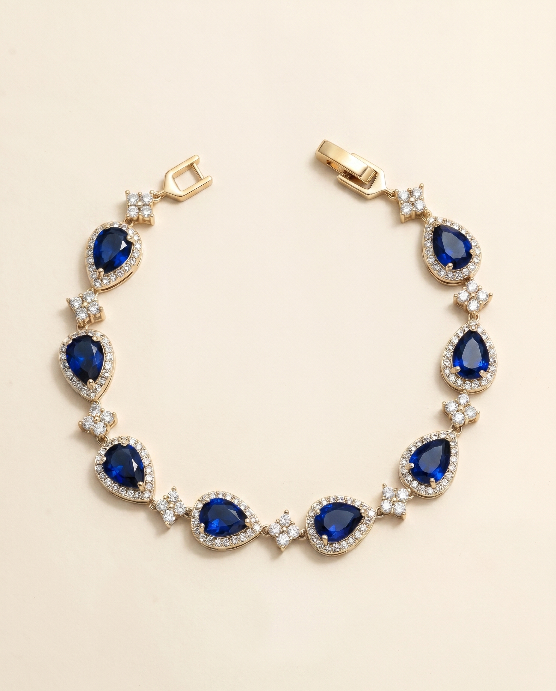 A gold bracelet adorned with blue gemstones, including diamonds, is displayed against a light background.