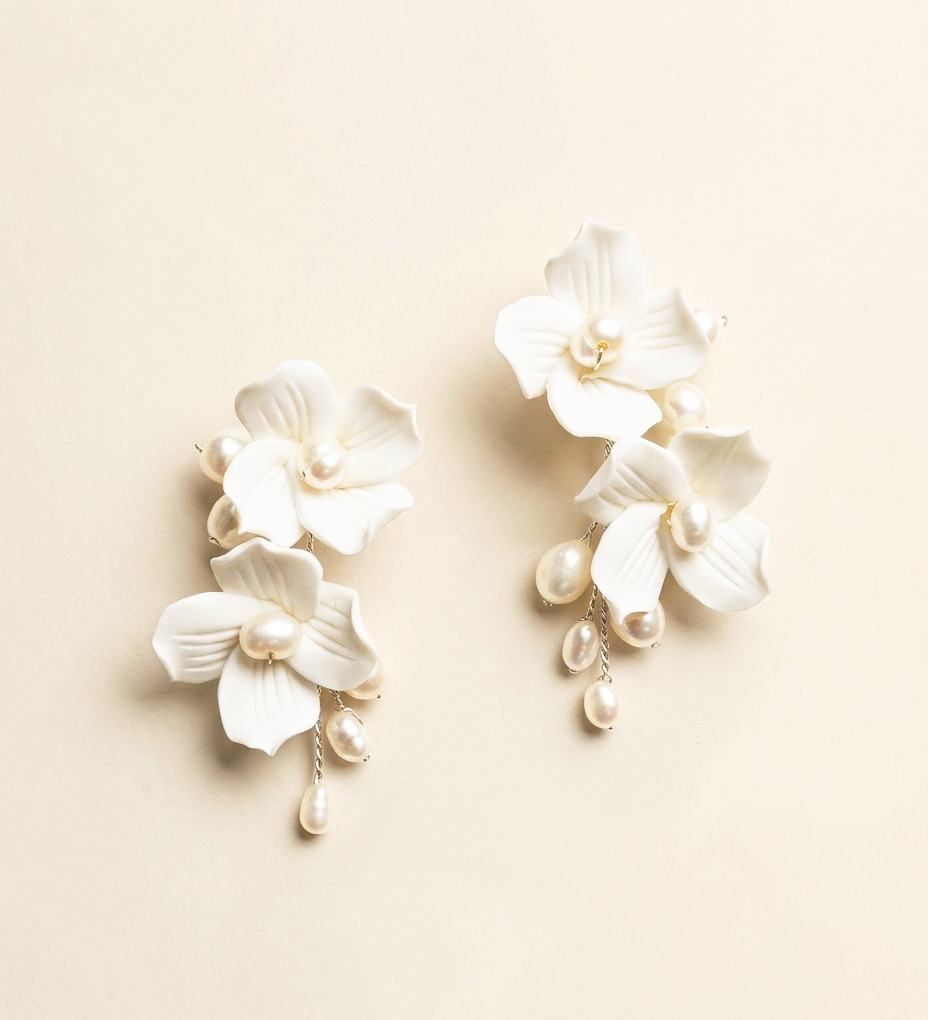 A pair of elegant white earrings with delicate white petals and dangling pearls.