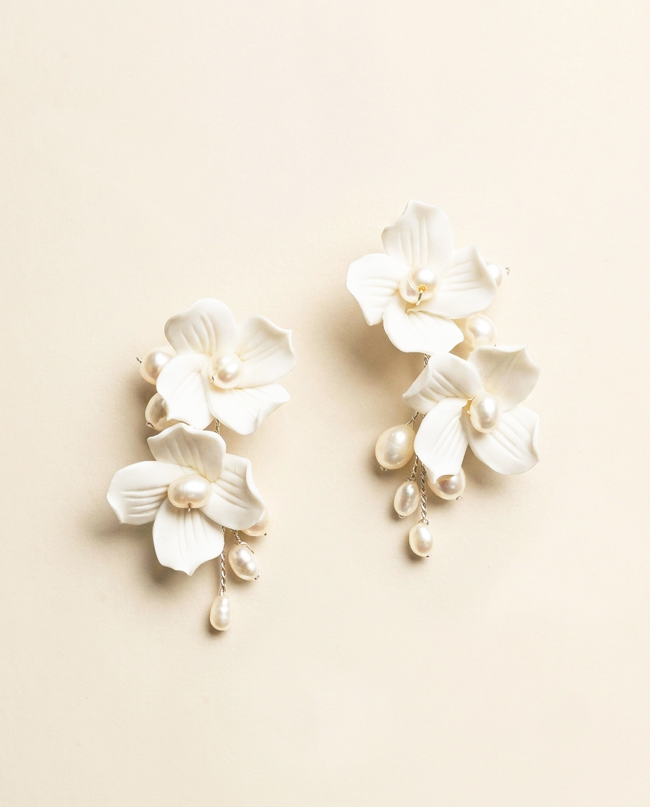 A pair of elegant white earrings with delicate white petals and dangling pearls.