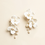 A pair of elegant white earrings with delicate white petals and dangling pearls.