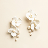 A pair of elegant white earrings with delicate white petals and dangling pearls.