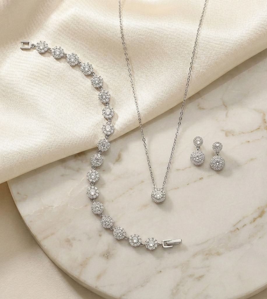 A necklace, earrings, and a bracelet are displayed on a marble surface, showcasing a collection of elegant jewelry pieces.