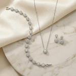 A necklace, earrings, and a bracelet are displayed on a marble surface, showcasing a collection of elegant jewelry pieces.