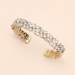 A gold bracelet adorned with numerous small, clear gemstones, including diamonds, set in a decorative pattern.