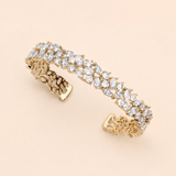 A gold bracelet adorned with numerous small, clear gemstones, including diamonds, set in a decorative pattern.