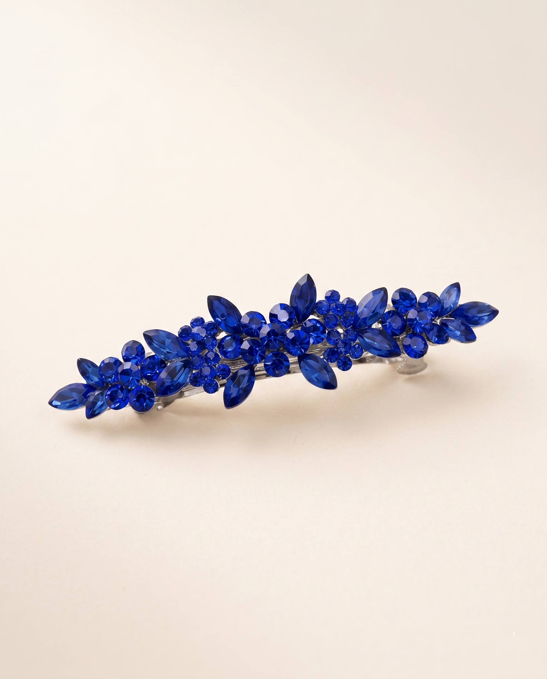 A decorative hair clip with blue gemstones arranged in a floral pattern.