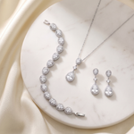 A necklace, bracelet, and earrings are displayed on a white marble surface, showcasing a collection of elegant jewelry pieces.
