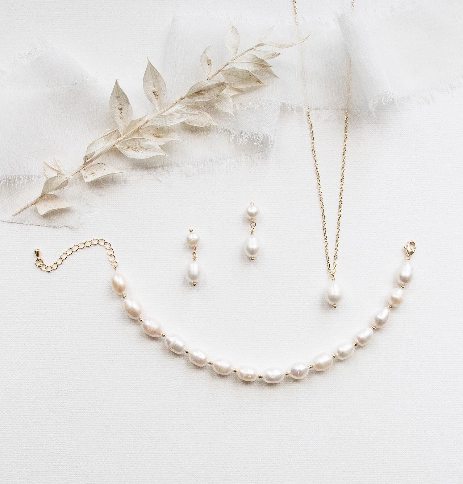 A collection of elegant pearl jewelry, including a necklace, earrings, and a bracelet, arranged on a white background.