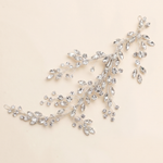 A delicate, sparkling crystal hair accessory with a branch-like design, featuring numerous small, clear gemstones.