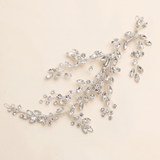 A delicate, sparkling crystal hair accessory with a branch-like design, featuring numerous small, clear gemstones.