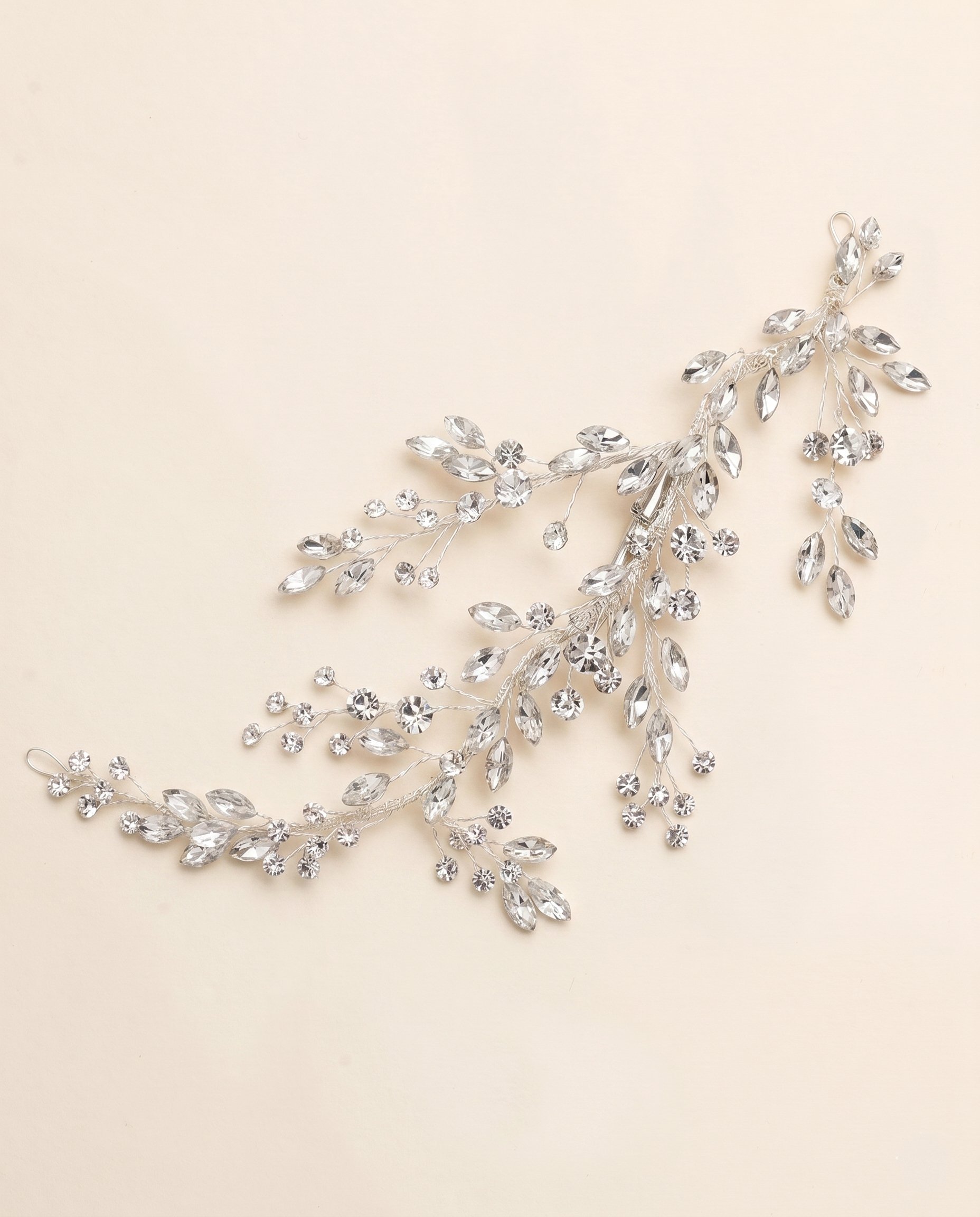 A delicate, sparkling crystal hair accessory with a branch-like design, featuring numerous small, clear gemstones.