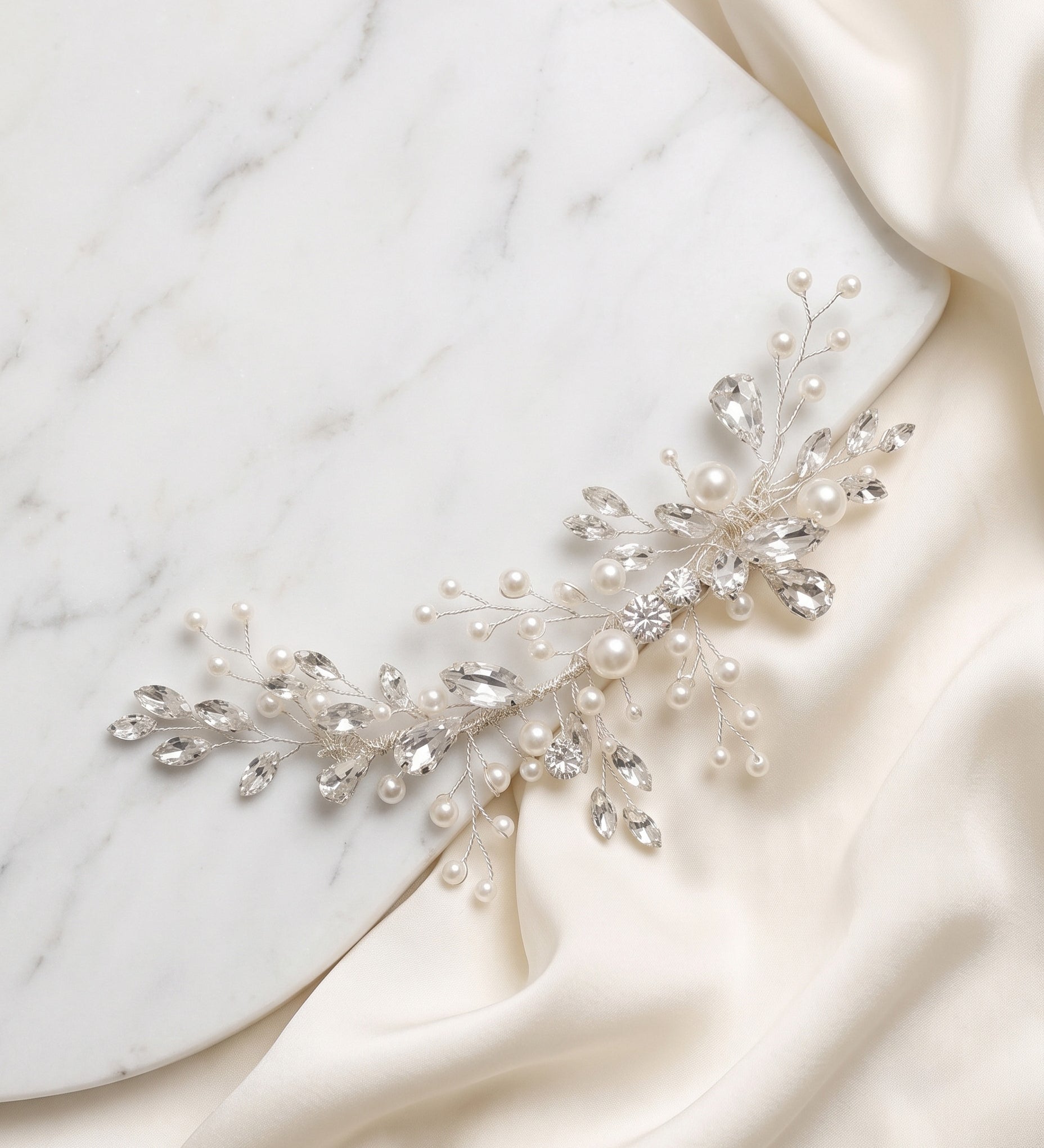 A decorative piece of jewelry, possibly a necklace or bracelet, adorned with small pearls and crystals, resting on a white marble surface.