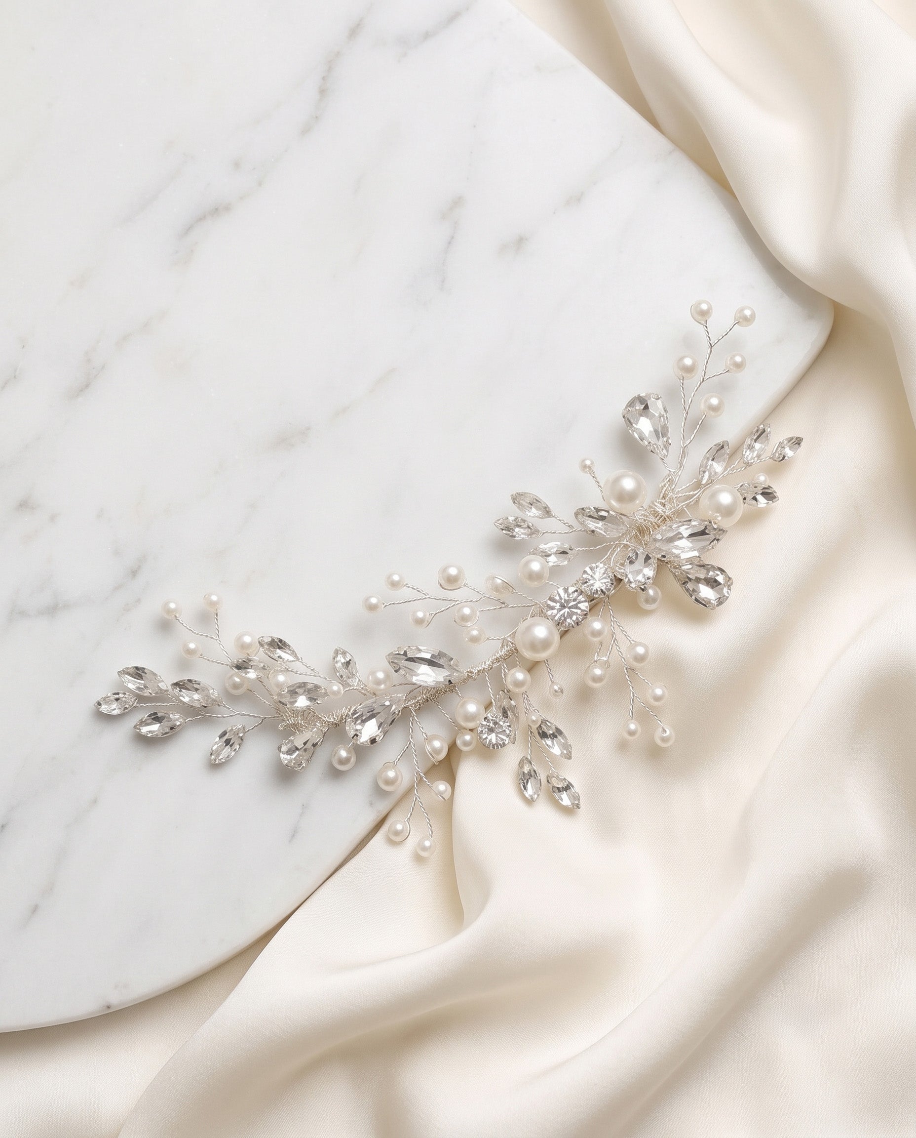 A decorative piece of jewelry, possibly a necklace or bracelet, adorned with small pearls and crystals, resting on a white marble surface.