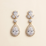 A pair of elegant gold earrings with large, clear gemstones set in a halo-like design.