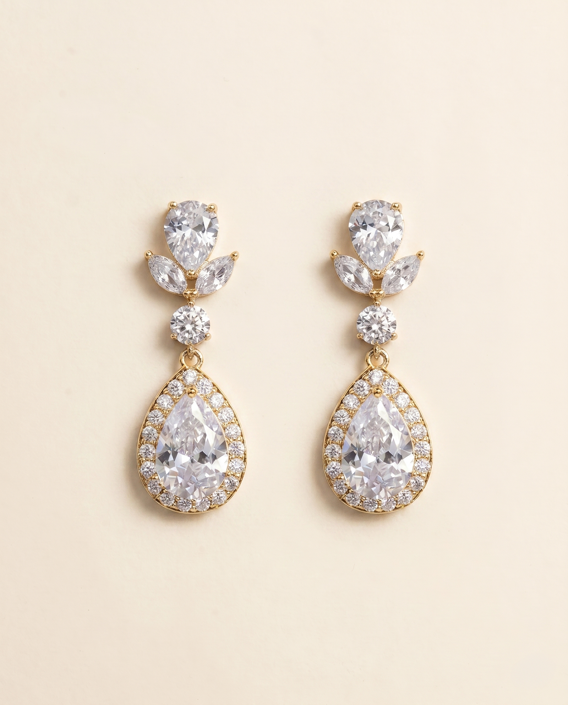 A pair of elegant gold earrings with large, clear gemstones set in a halo-like design.