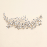A decorative piece of jewelry with a branch-like design, adorned with numerous small, clear gemstones.